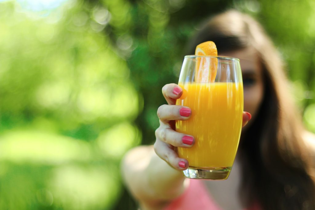 woman holding orange juice glass